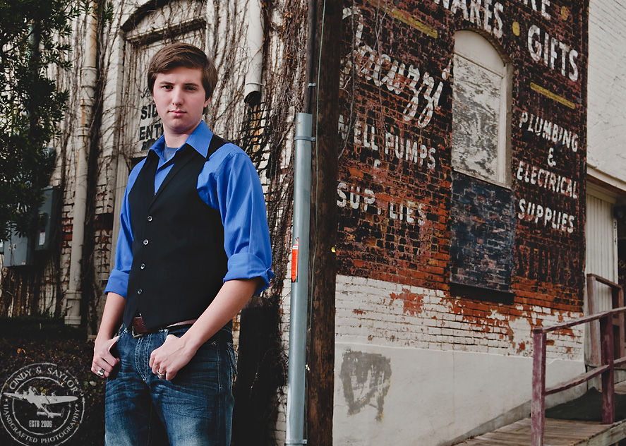 a brick wall with writing is a cool backdrop for a high school senior picture