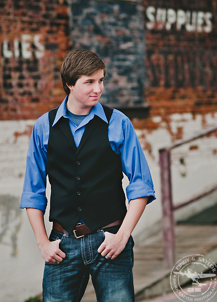 portrait of high school senior boy at the square in mckinney texas wearing blue shirt and black vest