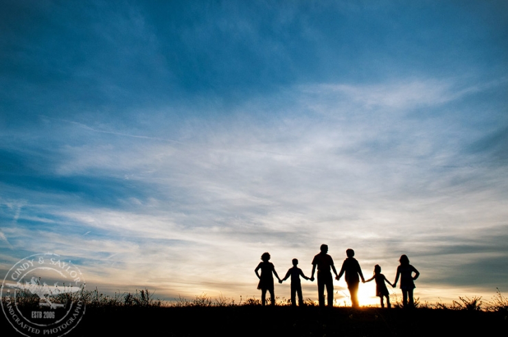 family portrait silhouette at sunset on hill